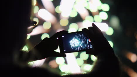 a woman admires the fireworks in the night sky take pictures with your smartphone