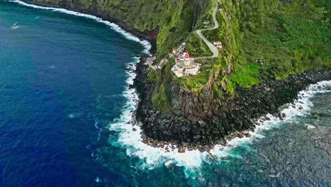 Lighthouse-on-green-seaside-cliff-at-São-Miguel,-Azores,-wide-aerial