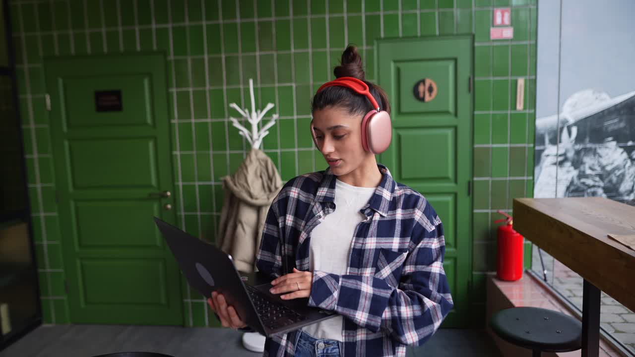 Mulher trabalhando em um café com fones de ouvido e laptop
