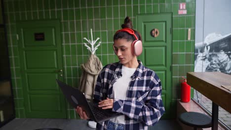 mujer trabajando en un café con auriculares y portátil