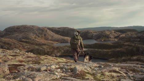 Hiker-With-His-Pet-Dog-Walking-In-Hildremsvatnet-Lake-In-Norway---wide-shot