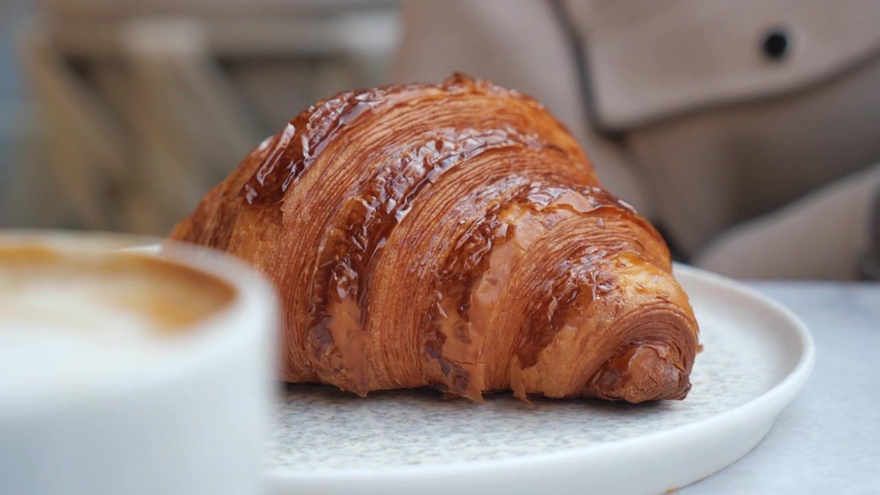 Persona che prende un cornetto fresco da un piatto in un caffè