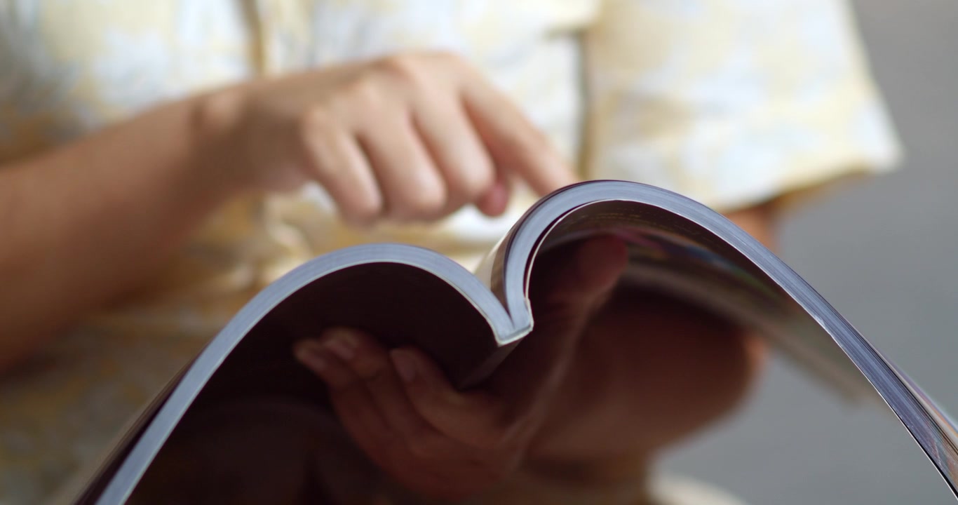 A person enjoys exploring a magazine absorbed in interesting content at home.