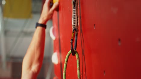 person rock climbing on a red climbing wall