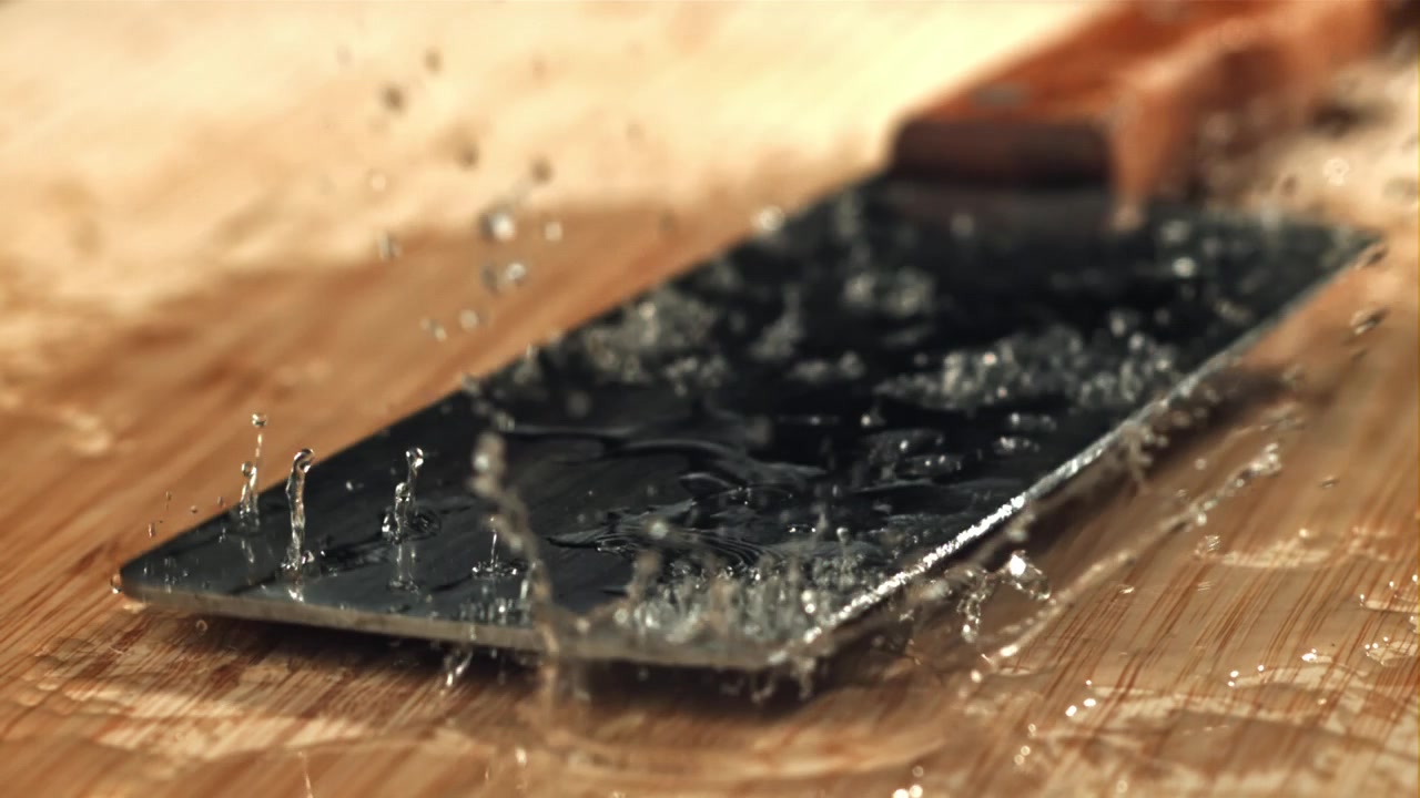 Water Splashing on Metal Spatula on Wooden Cutting Board