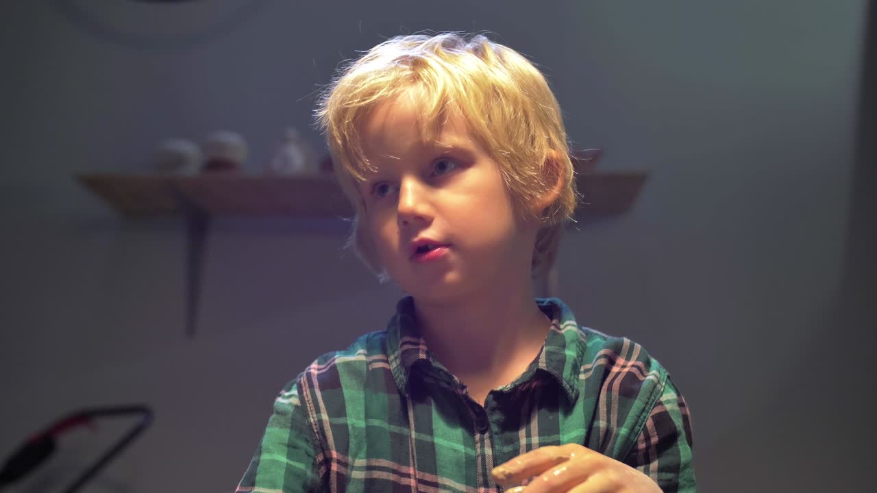 niño habla con la mujer mientras esculpe en el taller