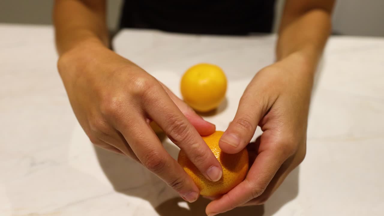 Manos pelando una naranja sobre una encimera