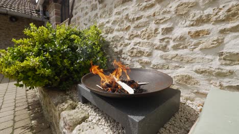 slow panning shot of orange flames in a cast iron fire pit against a stone wall background