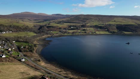 Flying-over-Highland-village-blue-water-bay-at-Idrigil-Bay-Uig-Isle-of-Skye-Scotland