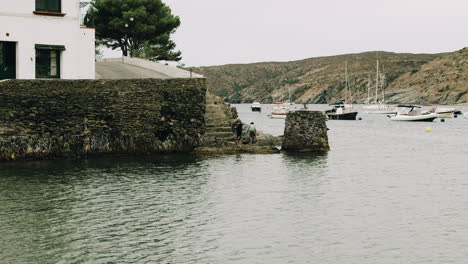 two boys fishing near a harbour in a small town