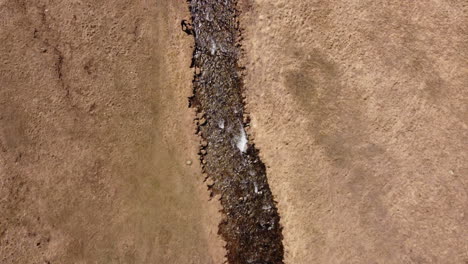 una persona sola, que contrasta con el río que fluye de color marrón oscuro en un lugar desierto