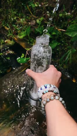botella de agua cristalina junto a un arroyo