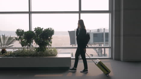 mujer hablando en teléfono móvil en la terminal del aeropuerto