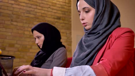 closeup shoot of two young beautiful muslim female office worker typing on the laptops on the workplace