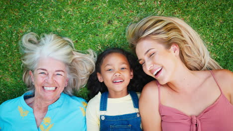 overhead portrait shot of smiling multi-generation female family lying on grass together