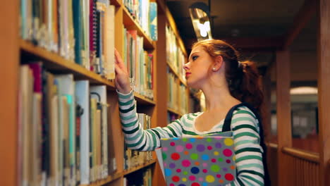 estudiante enfocado eligiendo un libro en la biblioteca
