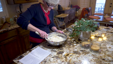 i woman folds whipped egg whites into a heavy dough