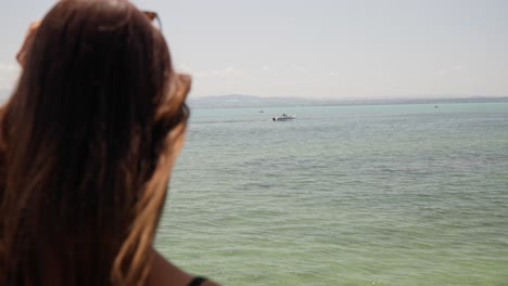 mujer quitándose las gafas de sol para ver la vista del lago constance bodensee cerca de friedrichshafen, alemania