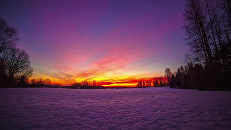 colorful sunrise on a partly cloudy morning over a meadow covered with snow