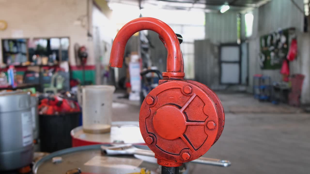 la cámara se aleja mostrando esta bomba de combustible de manivela de mano y el taller de reparación de automóviles, bangkok, tailandia