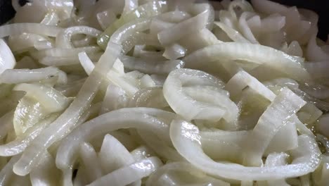 cerca de cebollas blancas chisporroteantes cocinar en aceite de oliva
