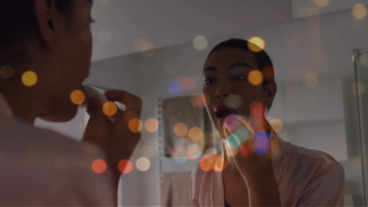 animación de manchas de luz sobre una mujer biracial aplicando lápiz labial.