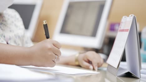 female hand planning working days with calendar at office