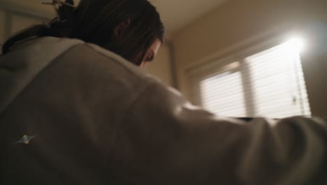low-angle shot of a woman checking and placing clothes while ironing in a warmly lit irish bedroom. domestic, natural, and relatable.