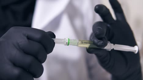 Closeup-view-of-professional-doctor's-hands-in-black-gloves-with-medical-syringe-in-hands,-getting-ready-for-injection