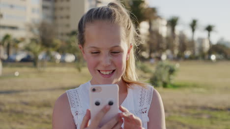 Retrato-Feliz-Chica-Caucásica-Rubia-Usando-Un-Teléfono-Inteligente-Disfrutando-Jugando-Juegos-Móviles-Sonriendo-Alegre-Satisfacción-En-El-Cálido-Parque-Al-Atardecer