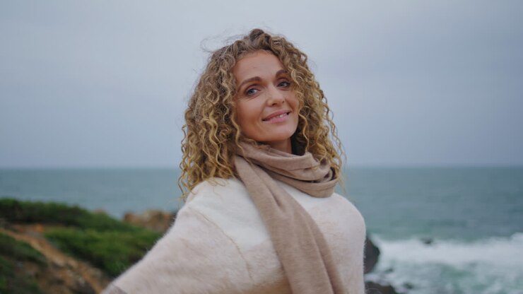 voyageur appréciez l'océan nuageux debout sur une belle rive de près. femme souriante