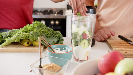 preparing healthy smoothie, person adding ingredients to blender in kitchen, at home