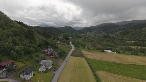 aerial view of countryside houses, road, and fields by the mountain in bergen, norway
