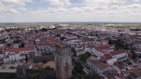 Old-stone-castle-in-town-of-Beja-in-cloudy-Portugal,-wide-aerial-pan
