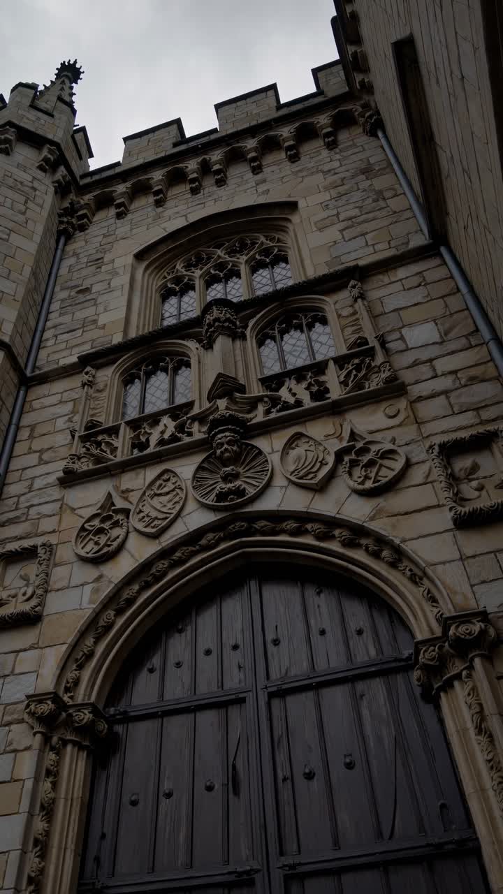 Inquadratura drammatica dal basso della facciata di un castello medievale sotto un cielo nuvoloso, perfetta per un video storico