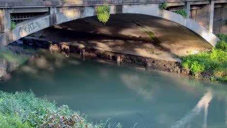 Water under the bridge with sun reflections. Corso Milano in Italy with Tronco Maestro canal
