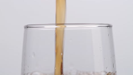 close up of fresh cola being poured in to the glass on white background