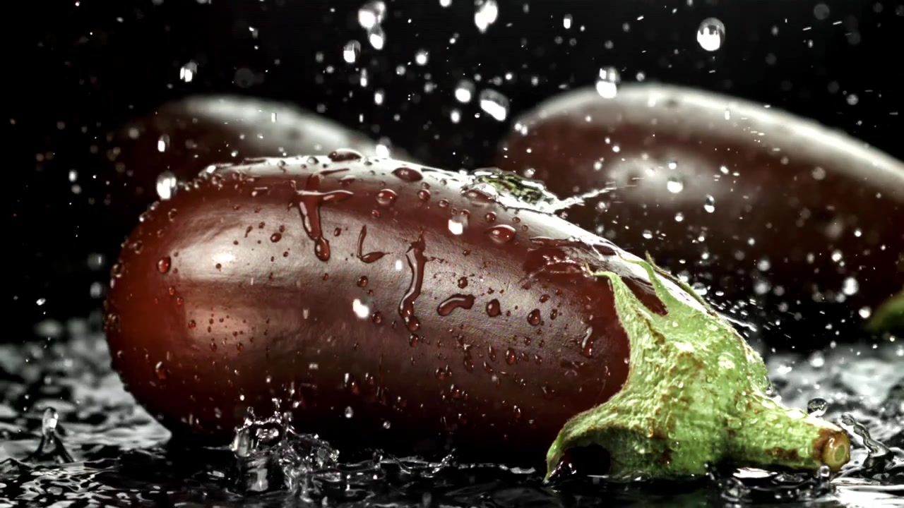 Färsk aubergine med stänkande vattendroppar mot svart bakgrund