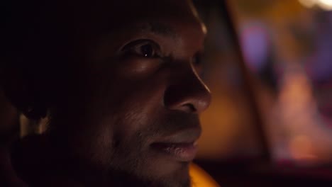 Close-up-a-man-with-Black-skin-and-a-beard-rides-through-the-evening-city-in-the-interior-of-a-modern-car-looks-and-enjoys-the-views-during-his-trip