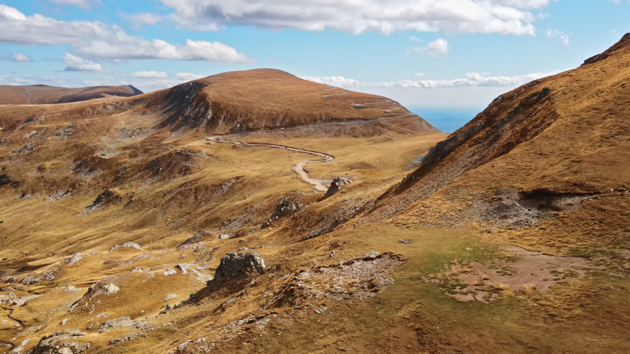 Aerial drone view of nature in Romania. Carpathian mountains, sparse vegetation, Transalpina road with cars