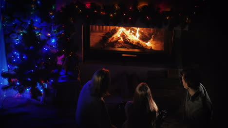 family with children sitting by the fireplace and new year tree top view