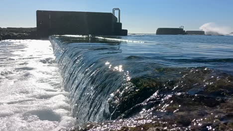 swimming pool of sea water completely overflowing, with the sea waves pouring the water out