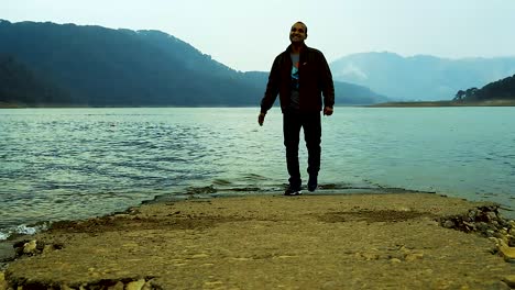 young man running towards the camera at lake shore at morning from low angle