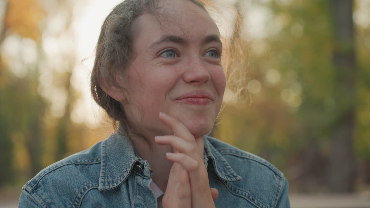 Dama feliz y agradecida. Mujer expresando felicidad en un entorno al aire libre. Mujer sentada al aire libre sonriendo con esperanza y gratitud. Mujer alegre vestida con mezclilla compartiendo momentos de alegría en un banco del parque.