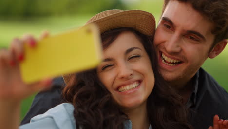 happy girl and guy saying hi on camera in park. man biting woman ear on picnic