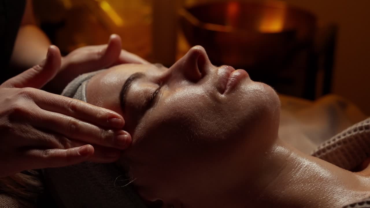 Nærbillede af kvinde, der modtager afslappende ansigtsmassage på et spa.