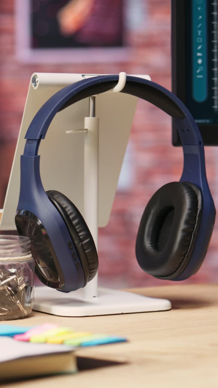 Vertical video Close up of headphones on home office desk next to PC screen