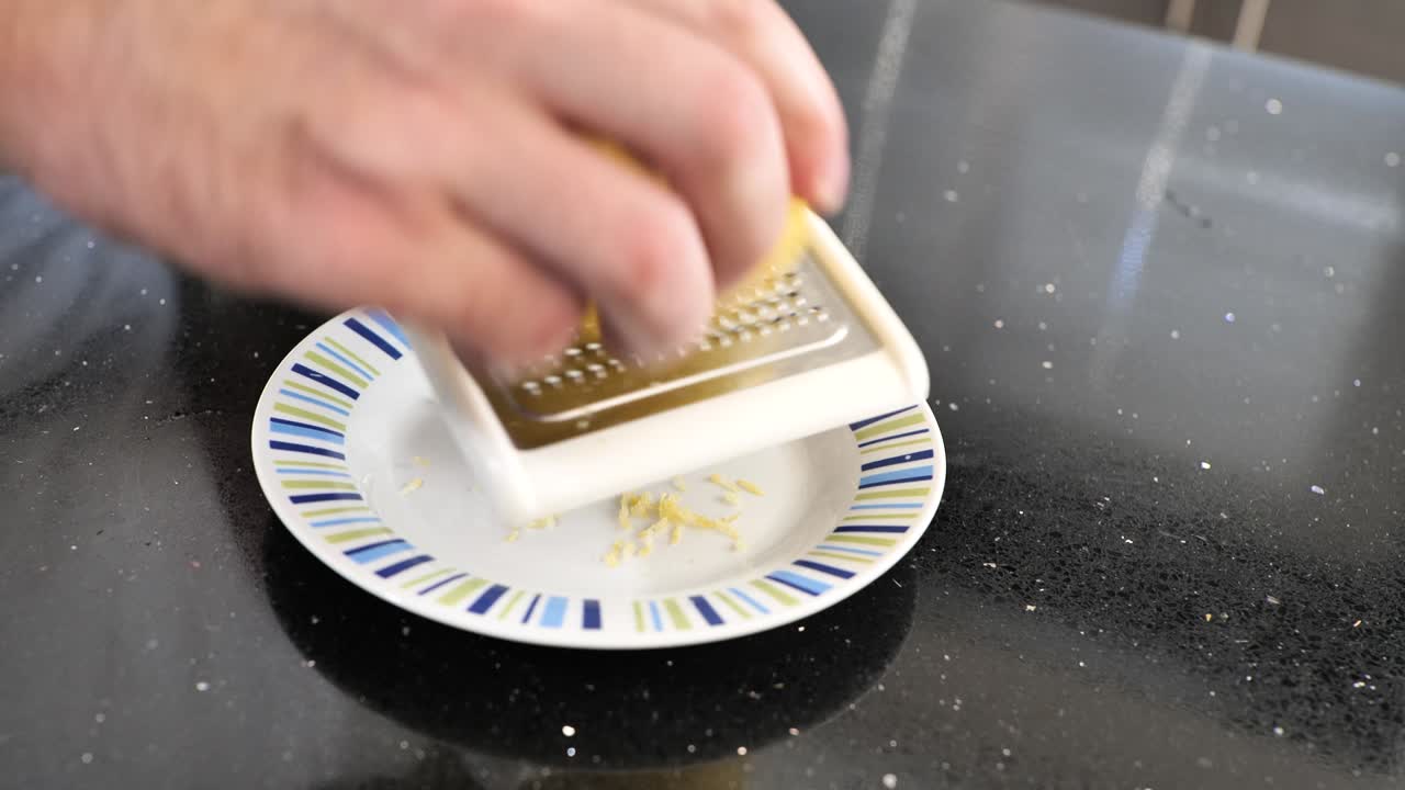 Primo piano dell'uso di una grattugia per rimuovere la scorza di limone