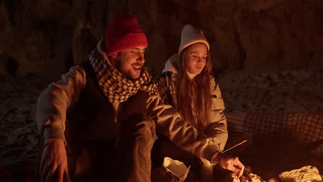 couple roasting marshmallows by a campfire in a cave