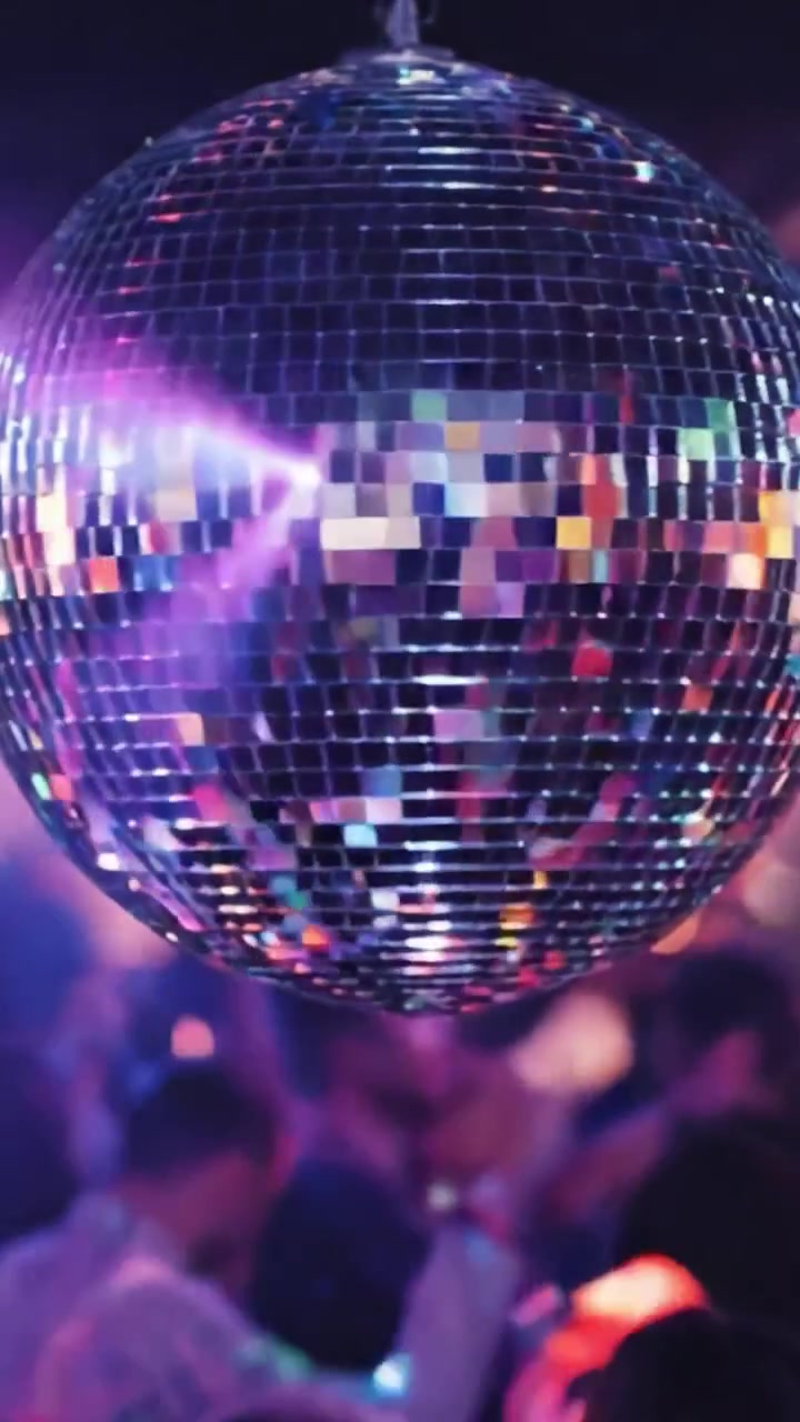 Una ipnotizzante palla da discoteca riflette luci vivaci e dinamiche di folla energiche, creando un'atmosfera elettrizzante in una vivace scena di festa piena di balli e celebrazioni